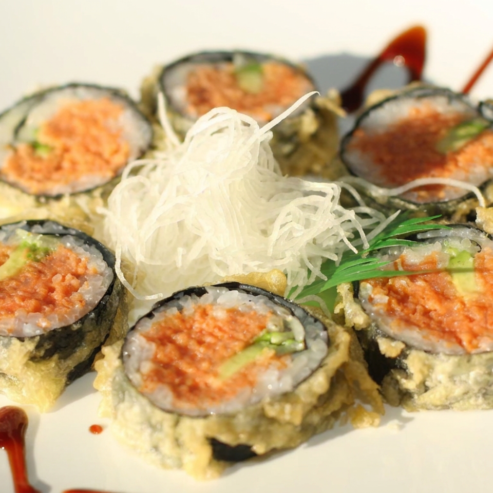 Platter of tempura sushi rolls topped with salmon roe, shredded daikon, greens, and artistic red sauce drizzles.